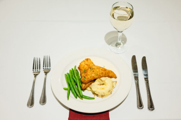 plate of meat and potatoes with wine glass, forks and knives