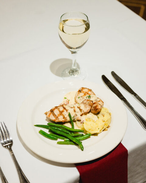 plate of meat and potatoes with wine glass, forks and knives
