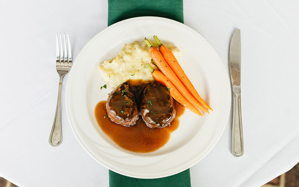 white dinner plate with meat, mashed potatoes, and carrots
