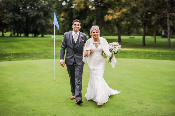 Bride and groom posing for photo on golf course
