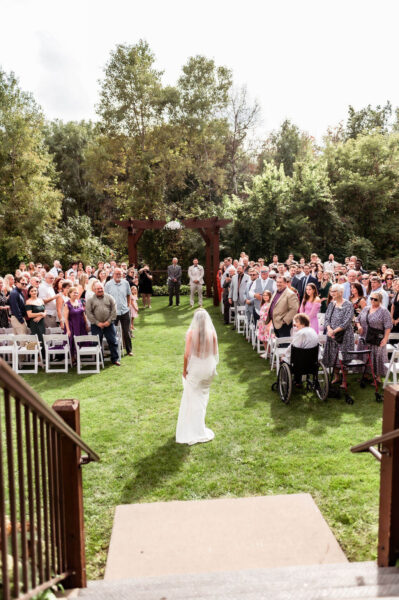 bride walking down the isle with wedding guests watching