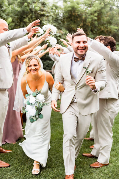 couple walking past wedding party smiling