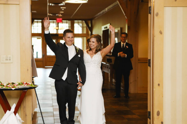 newly wed couple arriving at ceremony waving to guests